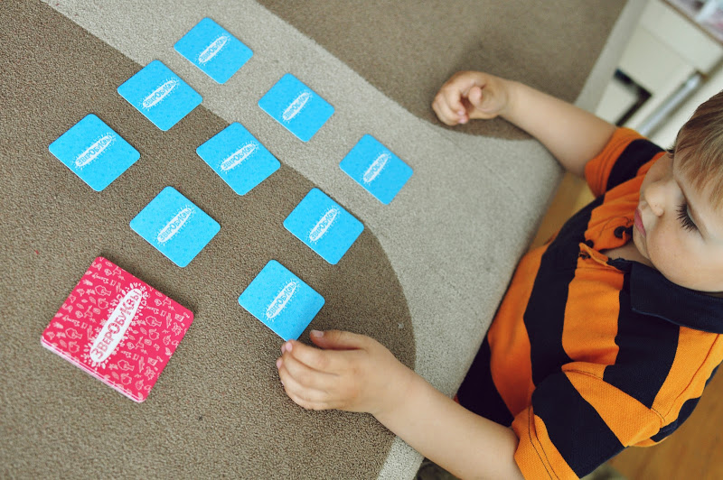 На столе выложены 3 на 3 карты с голубой рубашкой, рядом стопка карт с малиновой рубашкой.