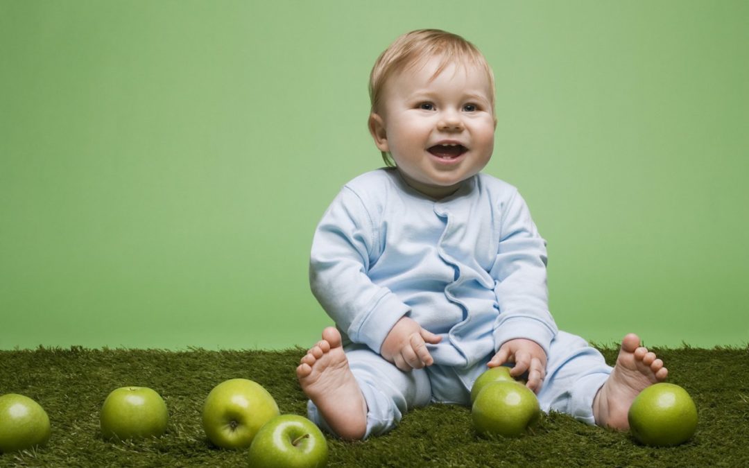 Малыш сидит среди яблок.