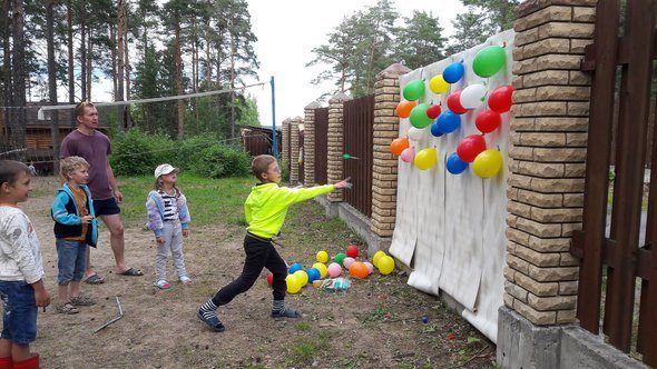 Дети бросают дротики в воздушные шарики.