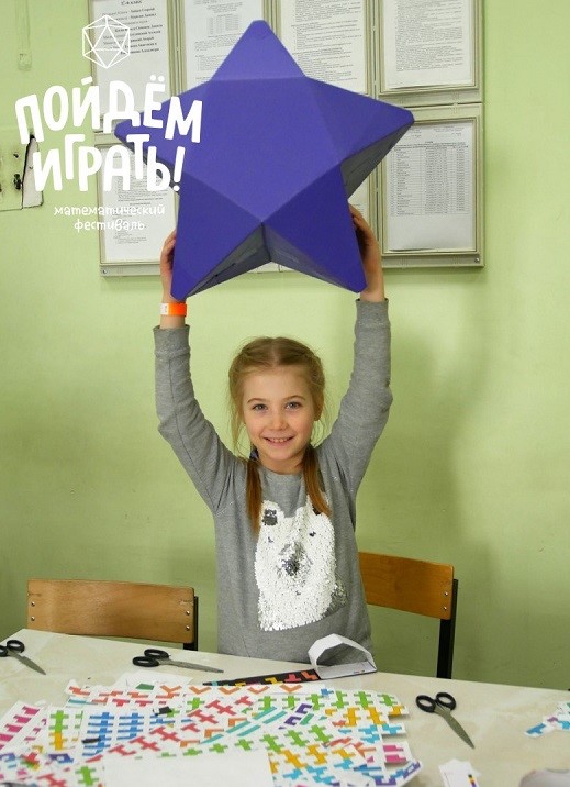 Девочка держит в руках большую картонную звезду.